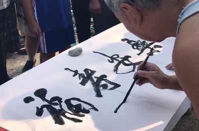 街頭藝術(shù)奇景 百歲書法家揮毫傳藝，三代同堂演繹文化傳承